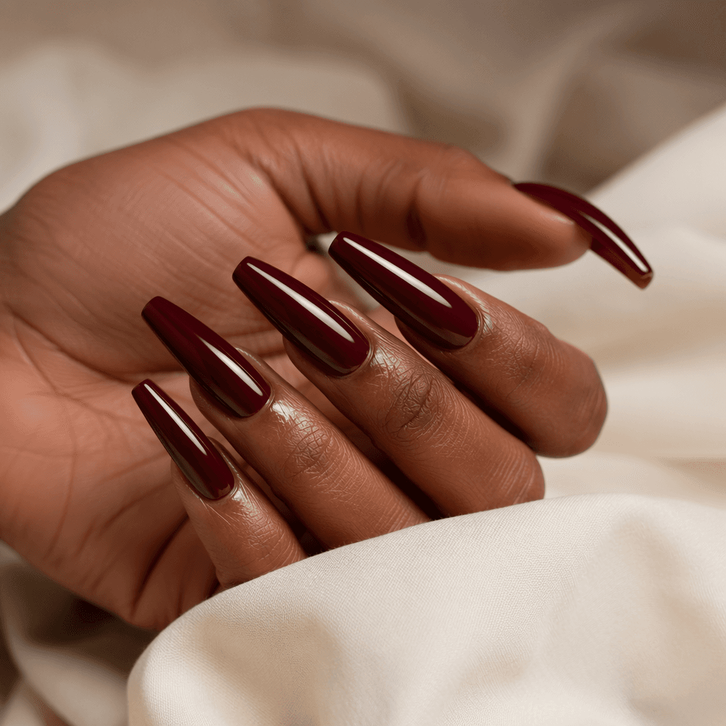 Long coffin builder gel nails in a deep burgundy with a glossy finish.